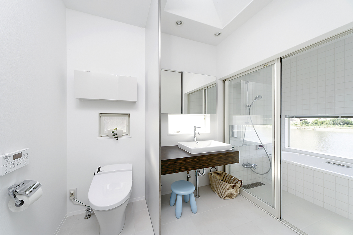 川の流れに癒やされながら入浴できる、真っ白にまとめられた爽やかな洗面・浴室