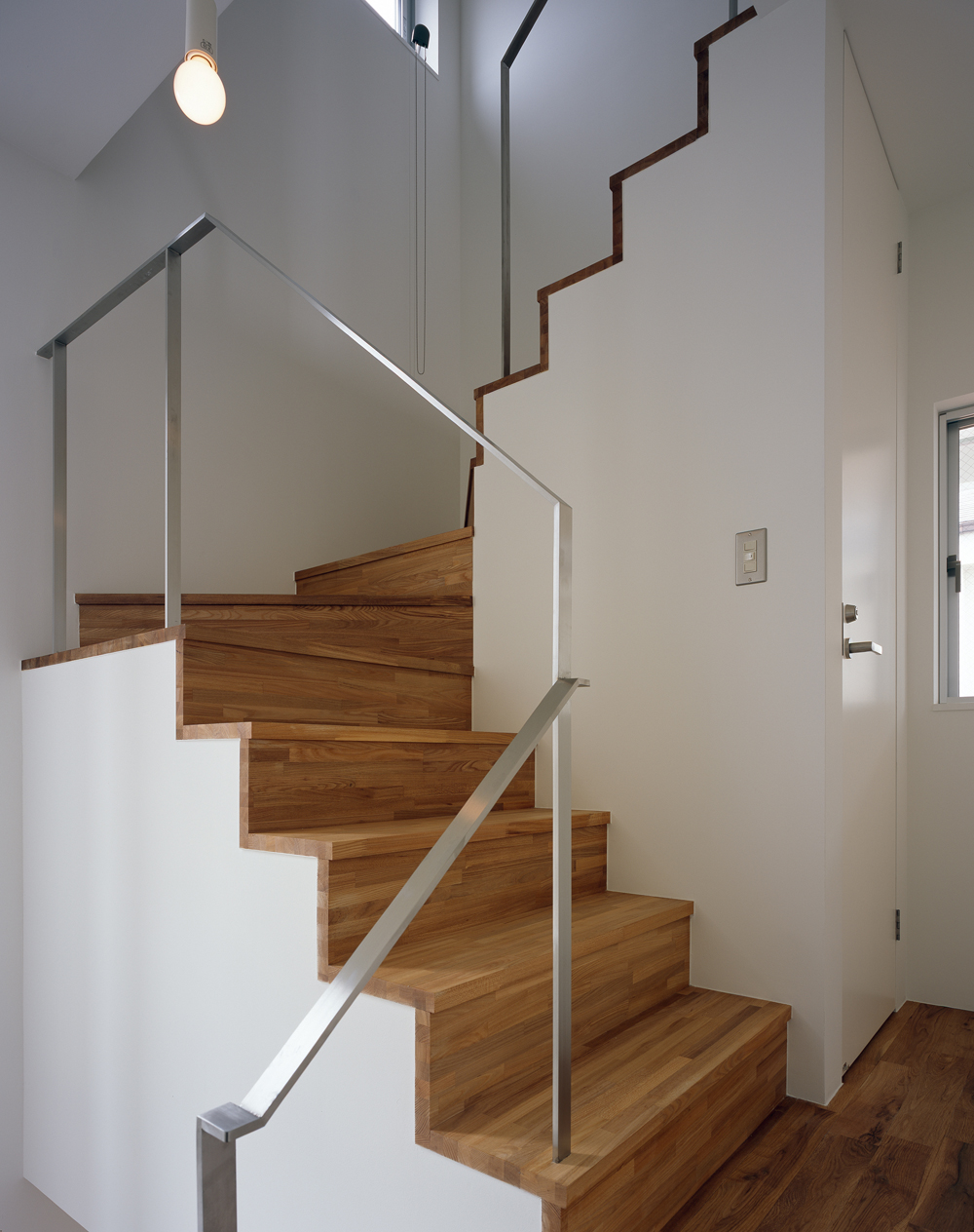 ステンレスヘアライン仕上げの手すりと集成材が、シンプルで上品な階段まわり