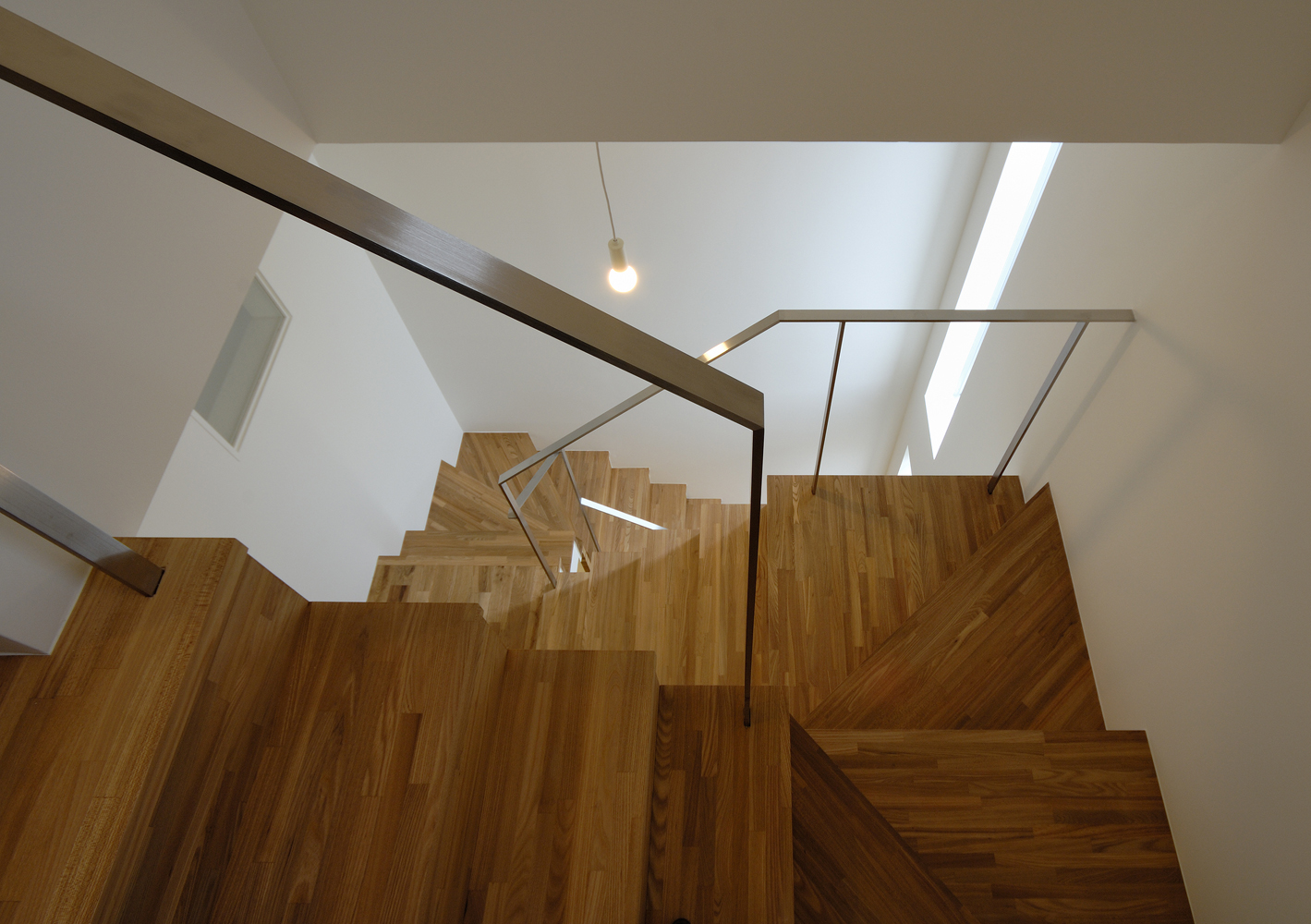 スリット窓からの光が広がる、立体的に繋がる階段