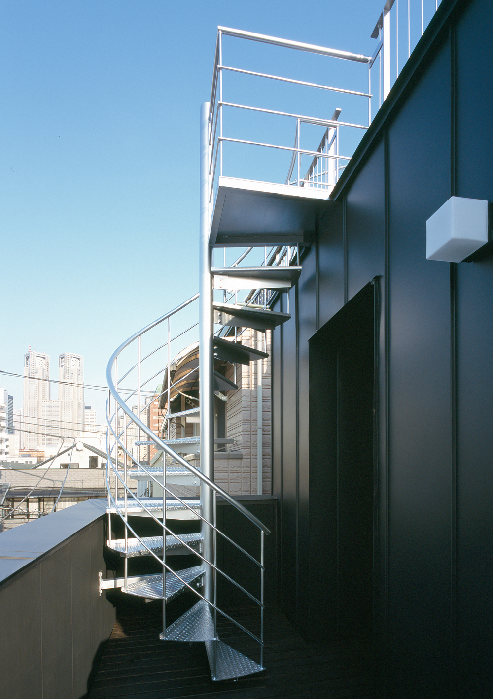 ハードな印象がマッチしている、黒のガルバリウム鋼板の外壁とシルバーカラーの外部階段
