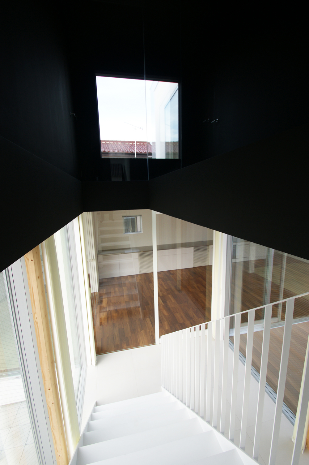 真っ黒の２階中壁と白く軽やかな１階スペースが、視覚的に楽しめる階段スペース