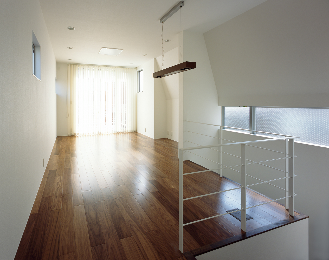 スキップフロアにより立体的に光が入る、ウォルナットのフローリングが似合う洋室