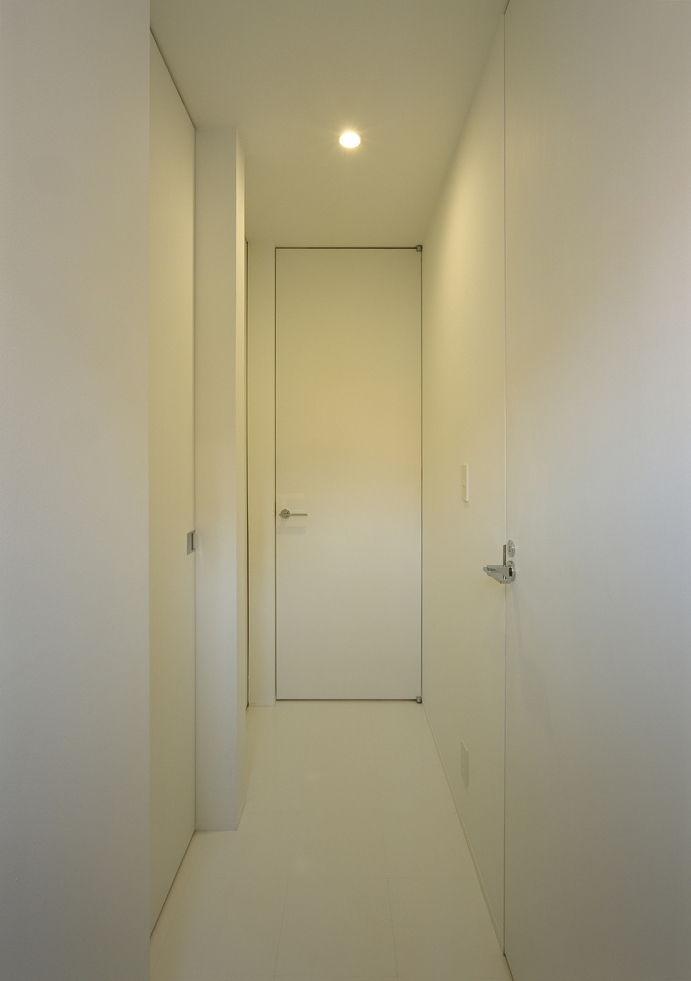 天井高まであるそれぞれの扉が、縦長の空間作りに役だっている廊下