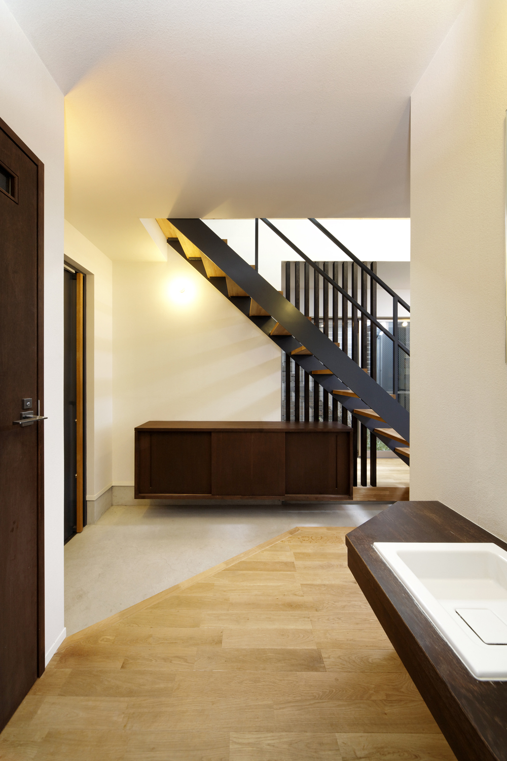 重くなりがちな玄関ホールに動きを出した、壁面から突き出した浮遊物のような下駄箱