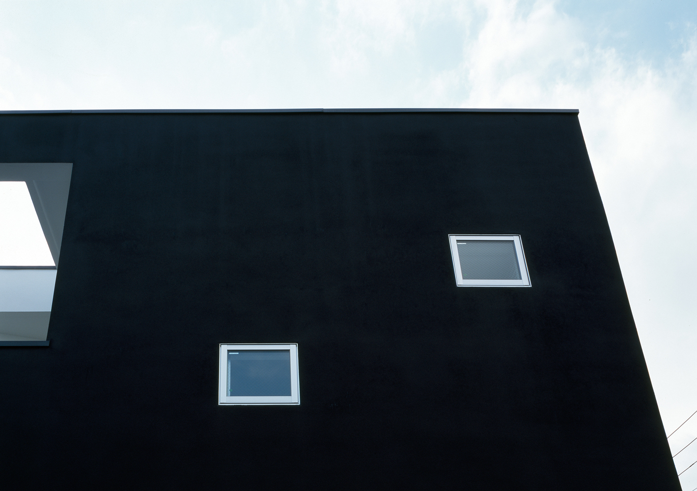 真っ黒な壁面に、小さなスクエア窓がかわいらしく配置する