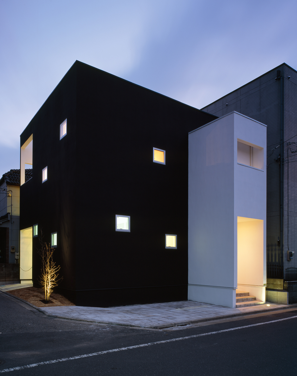 黒と白でできた建物にガラスタイルのように眩い光を放つ、夕方の外観