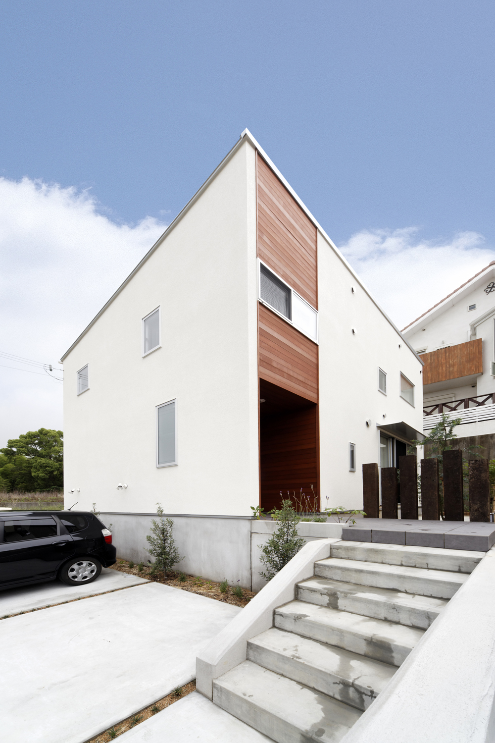 幅のある階段と、枕木をオブジェのように配置した壁が印象的な玄関アプローチ