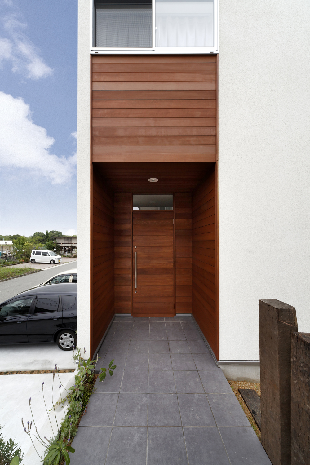 庇代わりに外壁からセットバックさせて玄関ドアを作った、木目の美しい玄関