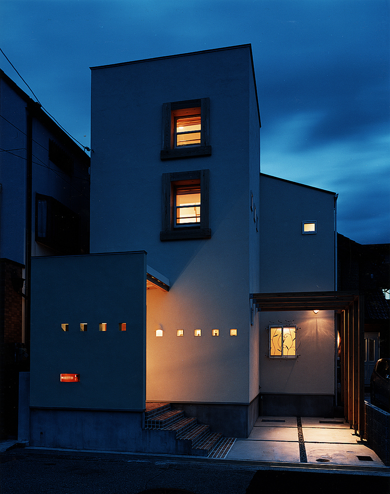 ニッチを兼ねた小さな小窓と、植物の動きを感じるアイアンの面格子が目を引く夜の外観