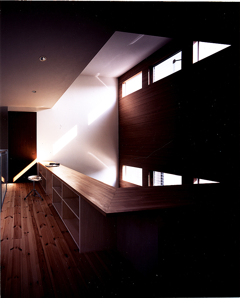 トップライトからの芸術的な光と安らかな影の世界が広がる、手すり部分を収納にした2階吹き抜け部分