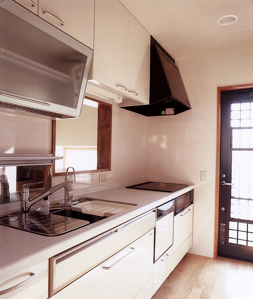 ガラス面を多く使った勝手口ドアから、明るい光が清潔なキッチンに入り込む