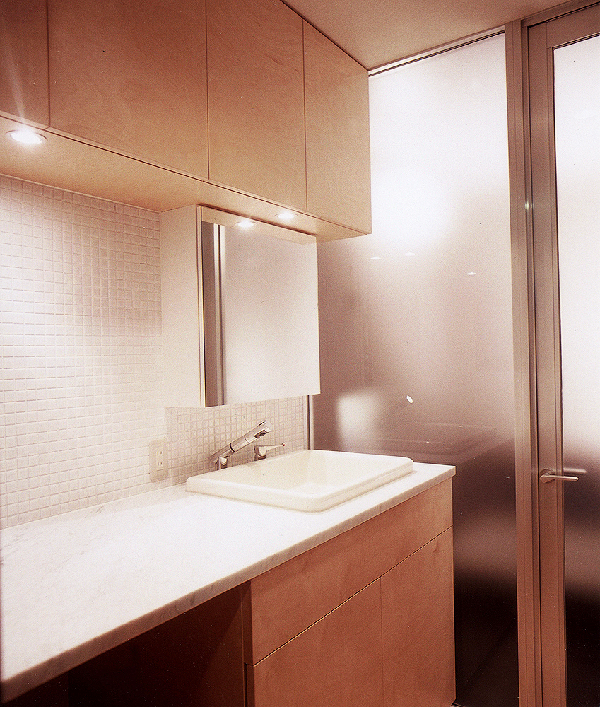 埋込み式コンパクト洗面器と、さまざまなテクスチャーのある素材を取り入れた洗面所