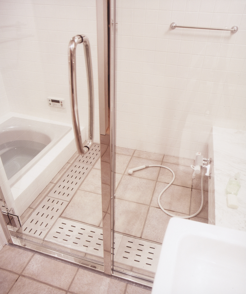 水気を切りやすいように排水部分を多めにした、ガラス扉でスッキリとまとめた在来浴室