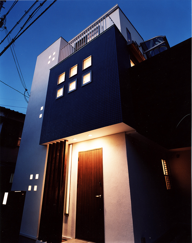 正方形の小さな窓から、建物自体が照明になったかのようにほっこり光を帯びる外観