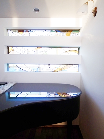 ステンドグラスが反射する漆黒のグランドピアノ