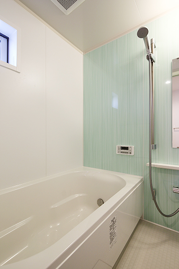 パステルグリーンの壁が爽やかなバスルーム