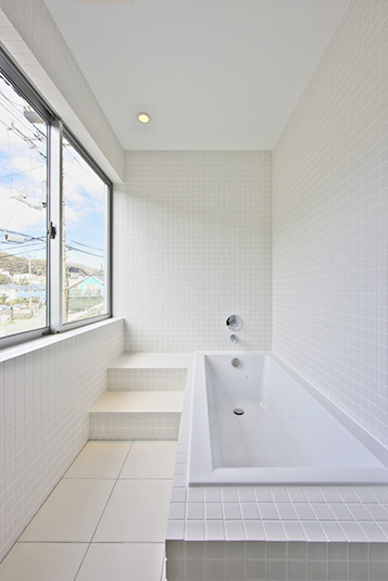 大きな窓のあるタイル張りの明るいバスルーム