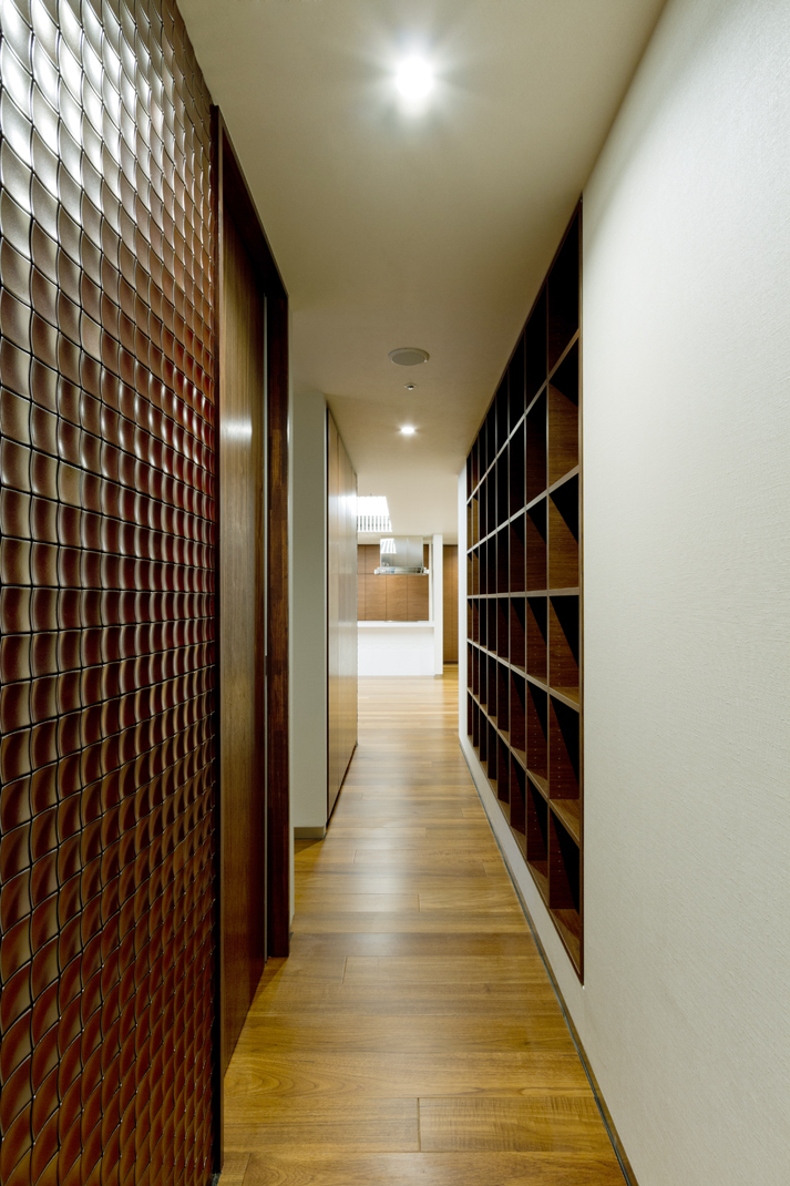 収納や、タイル張りの壁仕上げ材の色を合わせ、重厚感を演出した廊下