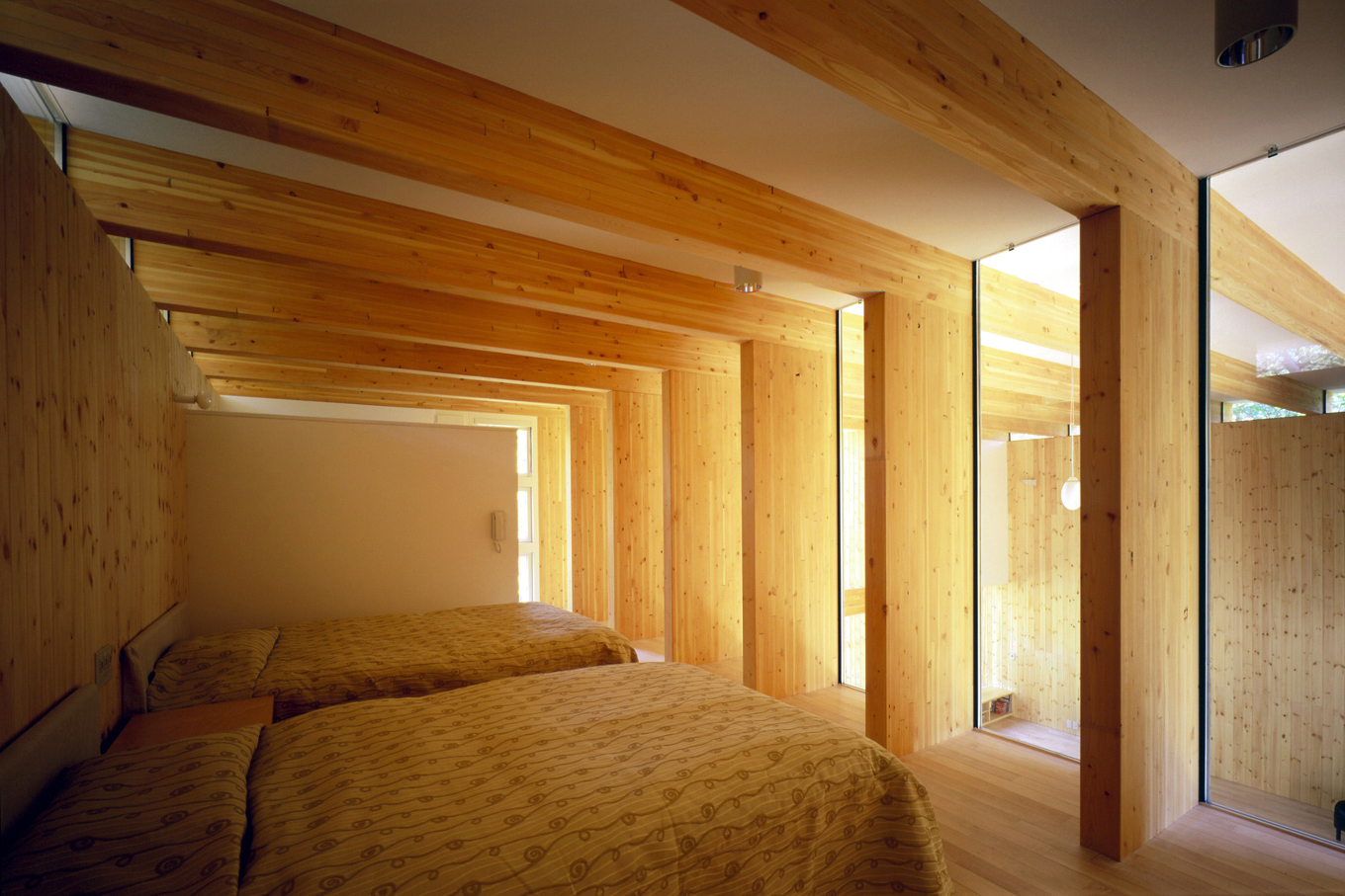 木の梁と自然光で包まれた寝室。日常から離れて自然を楽しむ