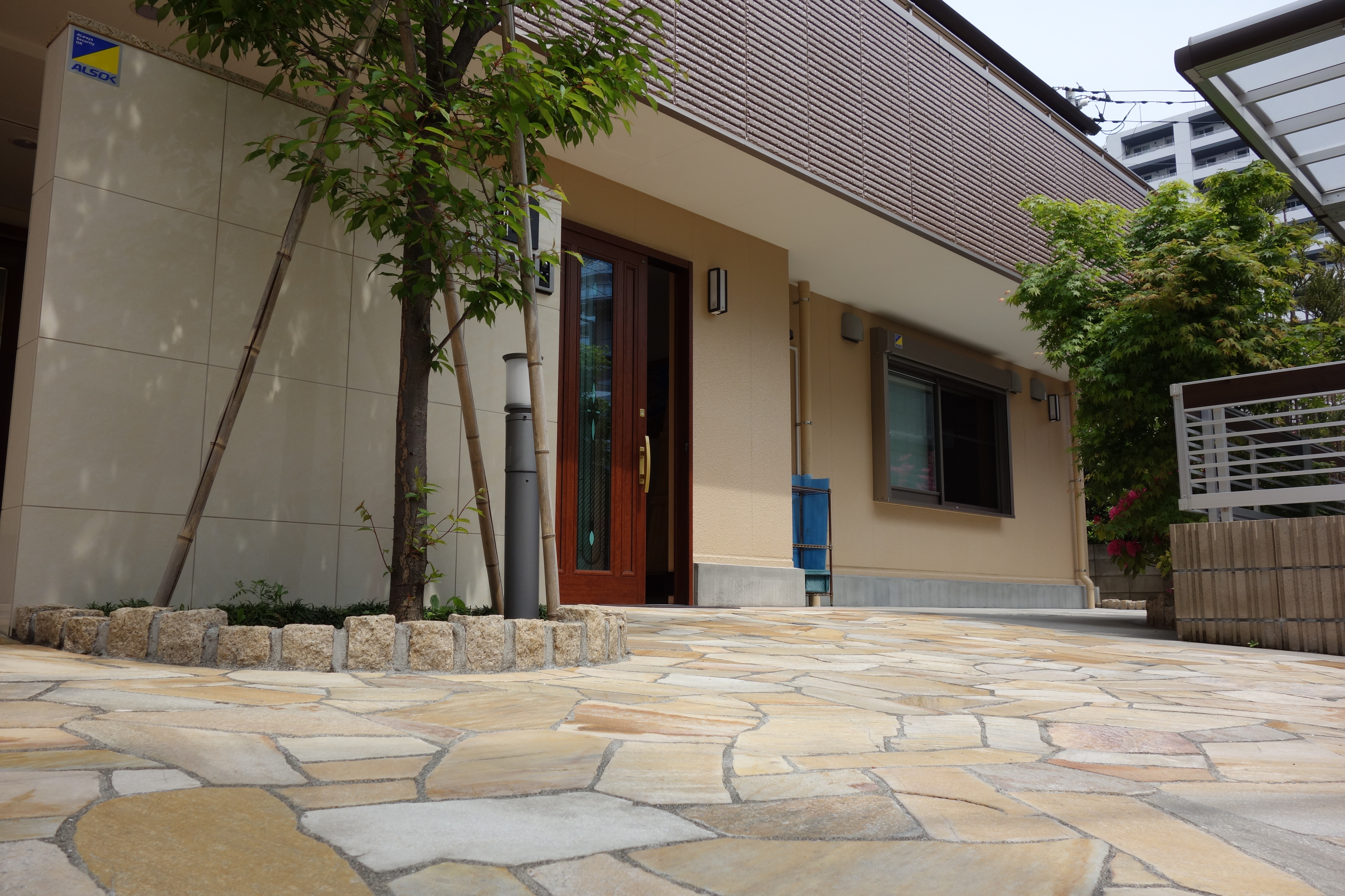 無造作のタイルと緑のある玄関ポーチ