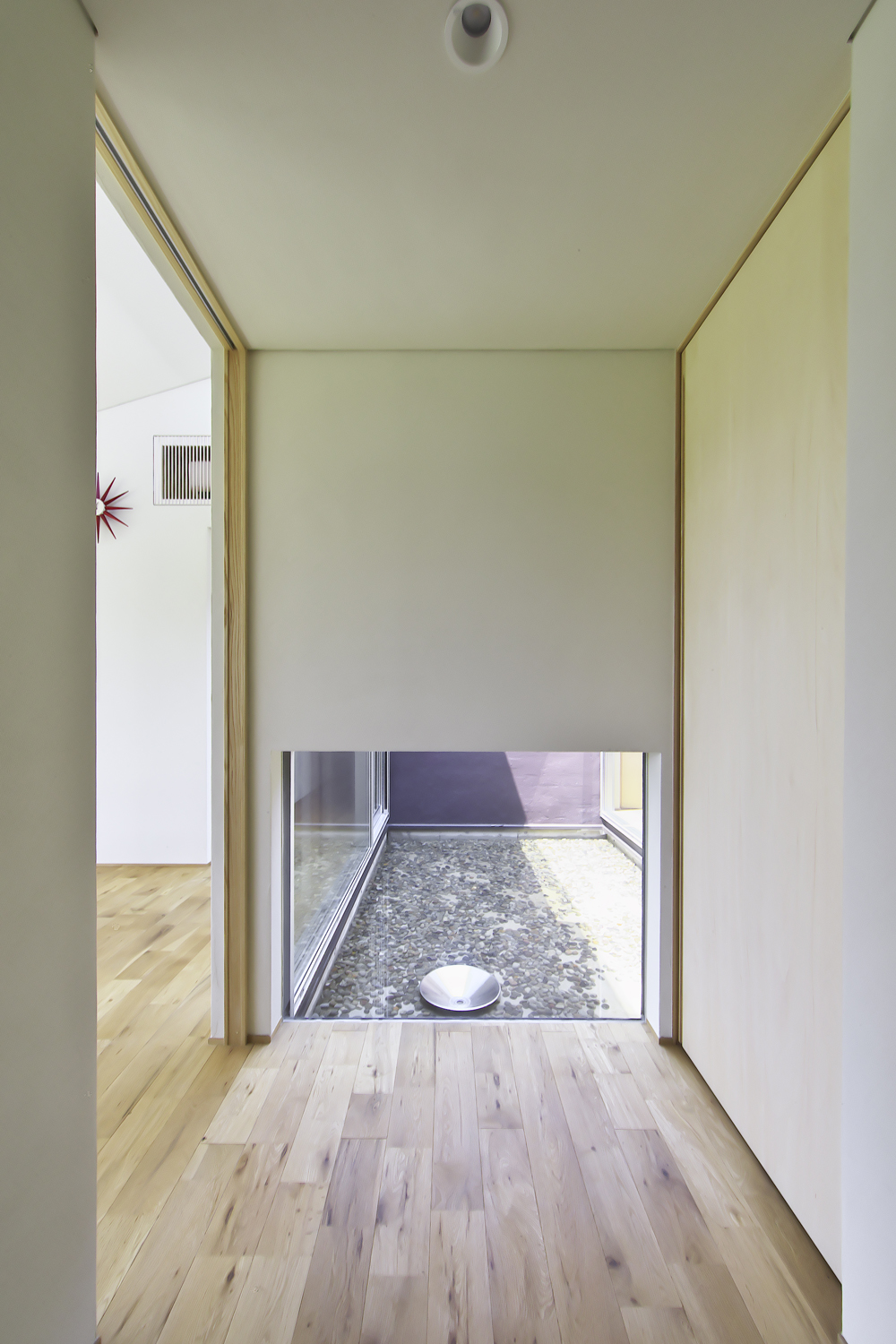 玄関を入ると、正面の地窓から覗く水盤が出迎える。