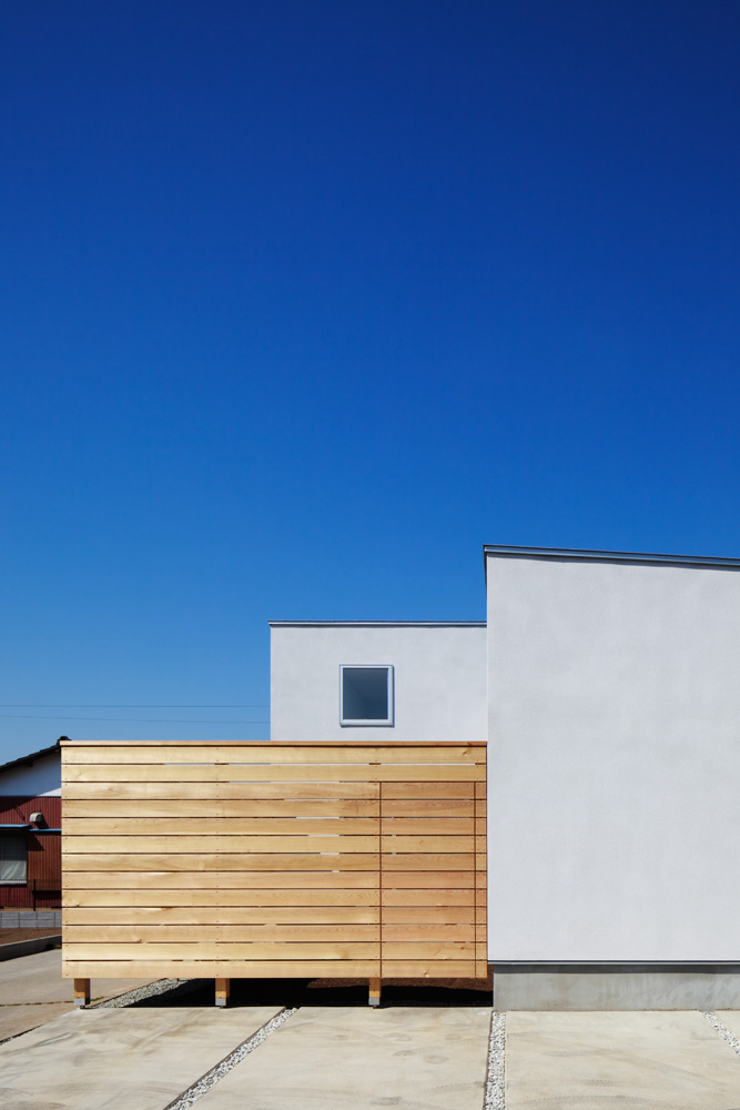 モルタル下地吹付塗装の継ぎ目のない外壁とレッドシダーの目隠し塀