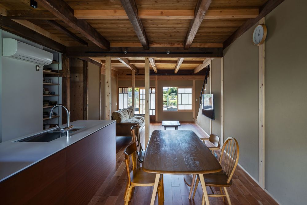 ダイニングから玄関方向。床はチェリー。キッチン面材はサペリ。濃い古材と白い新設材を中間色で取り持つ。