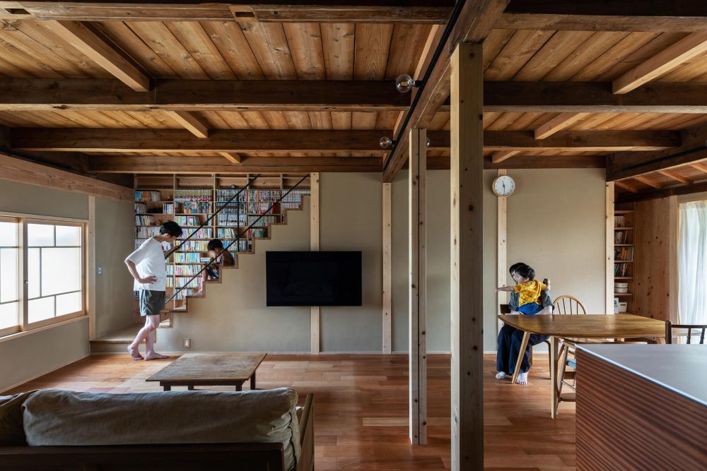 たくさんの蔵書のため階段周りに本棚を造作。左手の階段上は文庫・新書・コミックなど奥行きの浅い開架ライブラリ。右手の階段下は単行本・雑誌など奥行きの深い書籍を納める書庫。