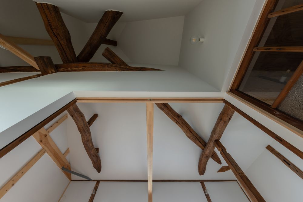 2階天井見上げ。寄棟の複雑な架構。壁・天井を白く塗った明るい空間。