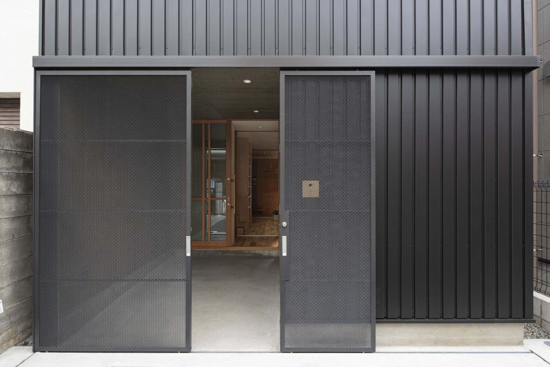 細身のエキスパンドメタル親子吊戸。普段は大きい戸を固定し小さい戸のみ開閉。自転車やバイクの出し入れ時は大小の戸を控壁へ収めて全開放。