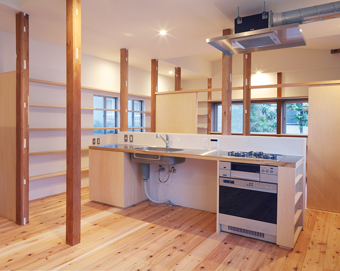 古い柱の残る一室空間の中央部に作付けたキッチン