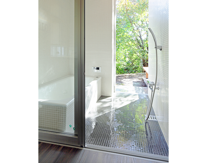 緑の庭につながる白いホーローのバスタブの浴室