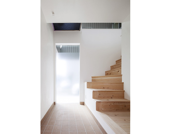 明るいエントランスから緩やかに2階に誘導する階段