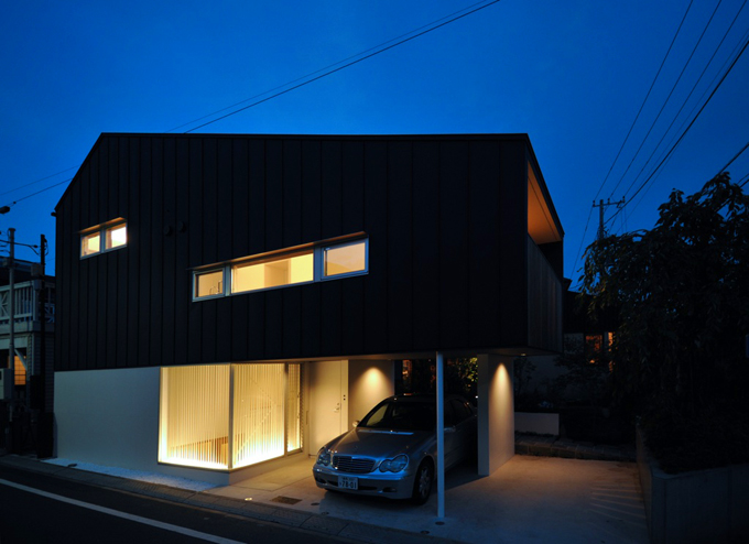 家の灯りと黒壁のコントラストが美しい夜の外観