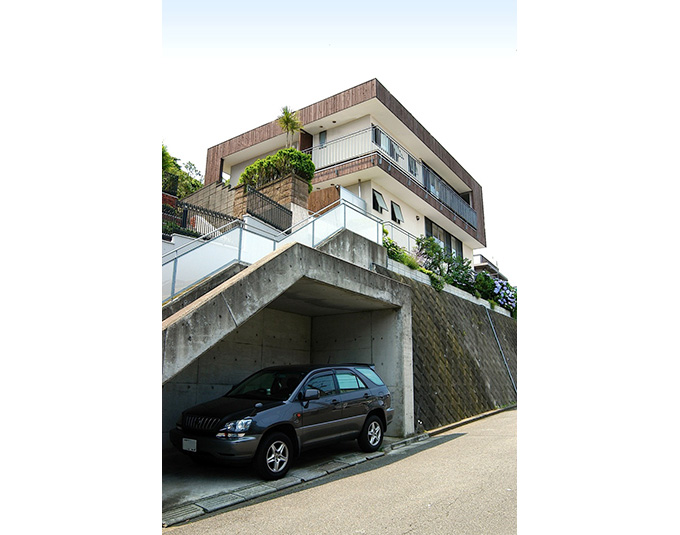 海と山の境目の崖に建つ、木の箱のような、二世帯住宅