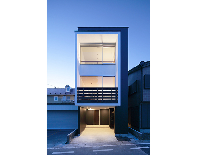 広い開口部から灯りの漏れる夕景外観