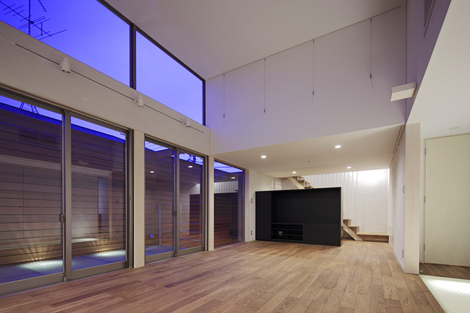 美しい照明が映えるウッドデッキを臨むリビング